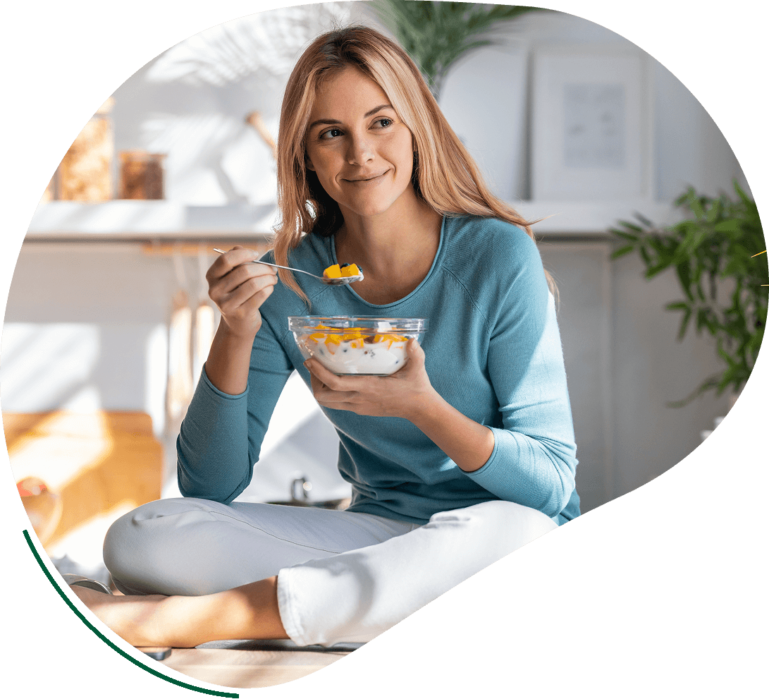 A woman sitting on the ground eating cereal.